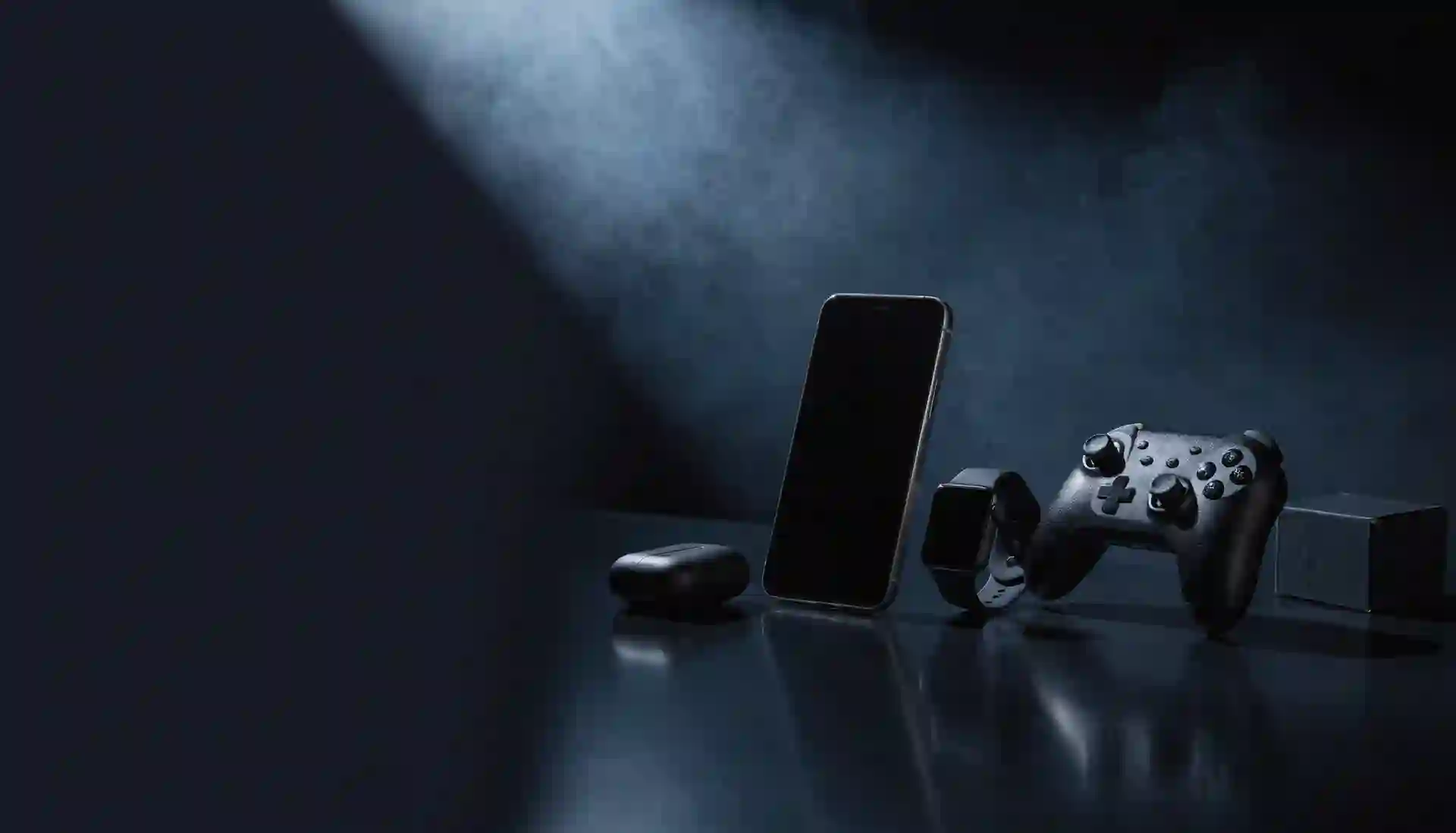 Conjunto de produtos de tecnologia — celular, fones, smartwatch, controle e caixa — organizados sobre uma mesa escura, representando a variedade de categorias da MicroTi